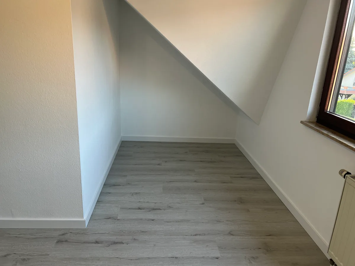 Zimmerecke unter der Dachschräge mit hellem Klick-Vinyl und Sockelleisten