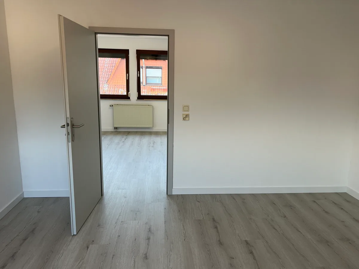 Blick durch die offene Tür ins zweite Zimmer, beide mit hellem Klick-Vinyl